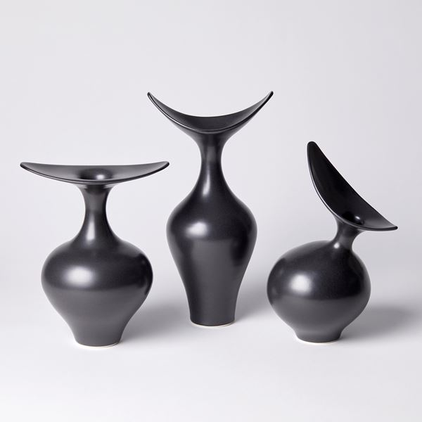 black round vase with off centre neck and offset stretched oval finned opening hand made from porcelain