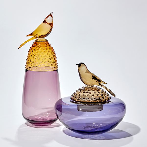 soft plum purple and golden amber vase with top third covered in raised dots with a stopper adorned with a golden amber bird hand made from glass