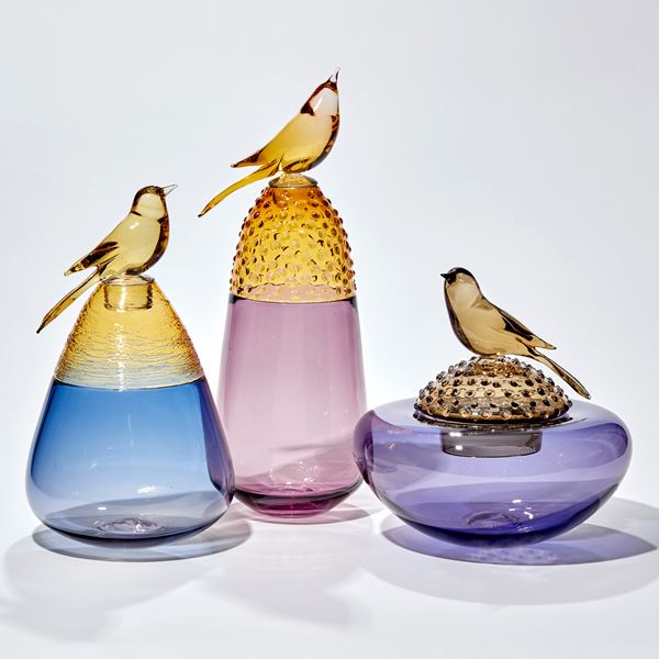 soft plum purple and golden amber vase with top third covered in raised dots with a stopper adorned with a golden amber bird hand made from glass