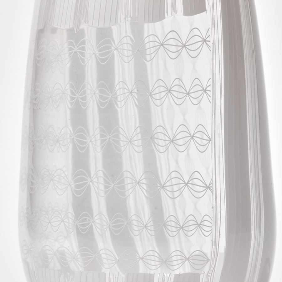 white and clear teardrop shaped vase with straight cut off top covered in intricate non symmetrical white patterns hand made from glass