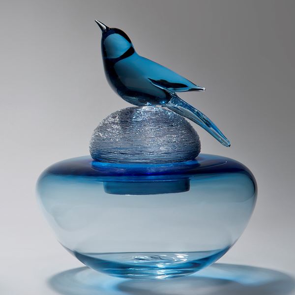 blue glass sculpture of funeral urn with bird on top