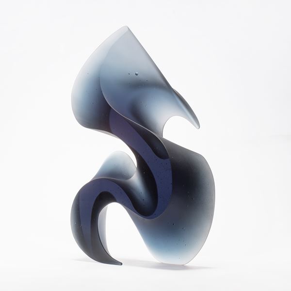 greyish blue tall curved and curling abstract shape made from cast glass with two flat polished sides and curved matt satin sides