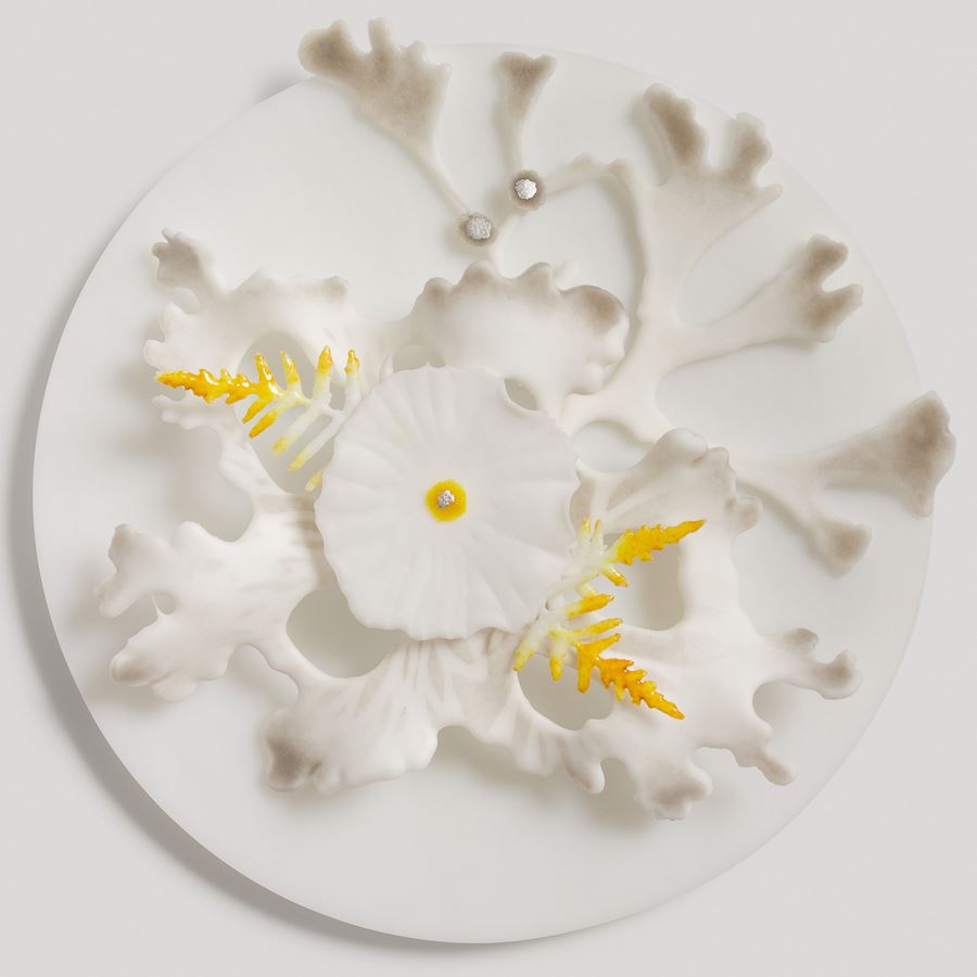 white round disc with white grey and yellow organic feathered and plant inspired raised organic detail handmade from glass