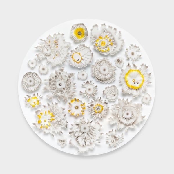 large round white disc covered in raised floral organic details creating florals fronds and lichen shaped elements hand made from glass