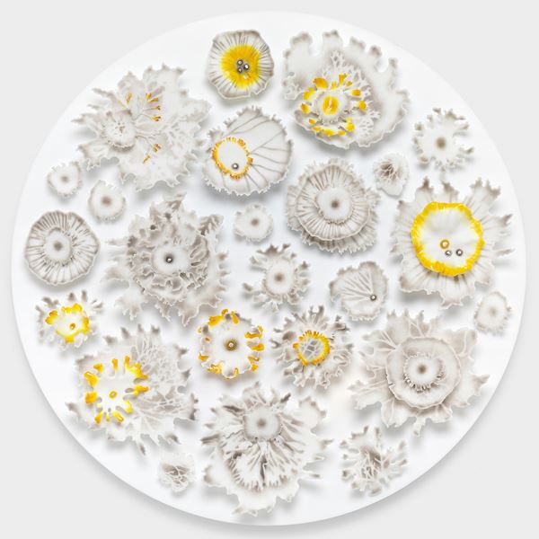 large round white disc covered in raised floral organic details creating florals fronds and lichen shaped elements hand made from glass