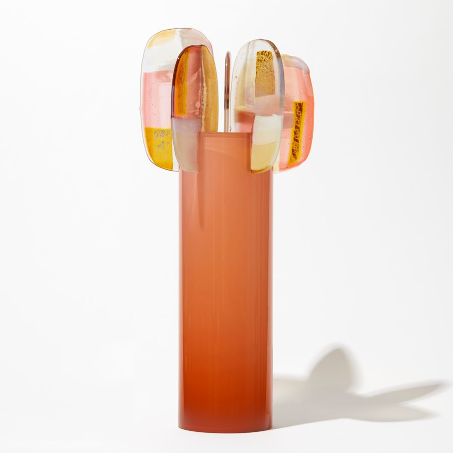 orange peach tall round glossy cylinder fading in intensity towards the top with five rounded lollipop like leaves with pink orange yellow and opal white abstract patterns perched at the top hand made from glass