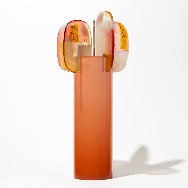 orange peach tall round glossy cylinder fading in intensity towards the top with five rounded lollipop like leaves with pink orange yellow and opal white abstract patterns perched at the top hand made from glass