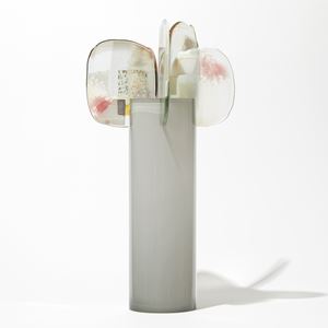 soft grey glossy cylinder with five perched abstract petals at the top each with patches of colour in pink grey opal white and gold hand made from glass
