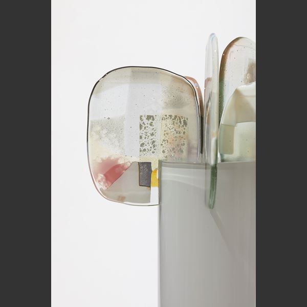 soft grey glossy cylinder with five perched abstract petals at the top each with patches of colour in pink grey opal white and gold hand made from glass