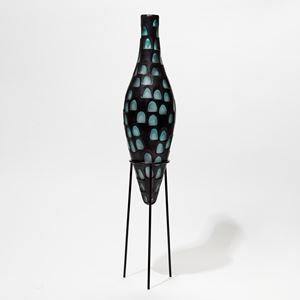 tall elongated bottle form with cut out rounded detail like an abstract peacock feather in black and jade hand made from glass with metal stand