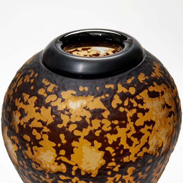 amber and black organic textured amphora bottle with black cuff opening and black steel stand