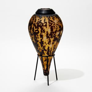 amber and black teardrop shaped abstract bottle with black cuff on the top hand made from glass with black metal stand 