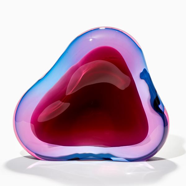 soft fluid triangular standing shape with interior cavity lined in brilliant white that is surrounded in transparent layers in turquoise and pink which merge creating further hues handmade from glass