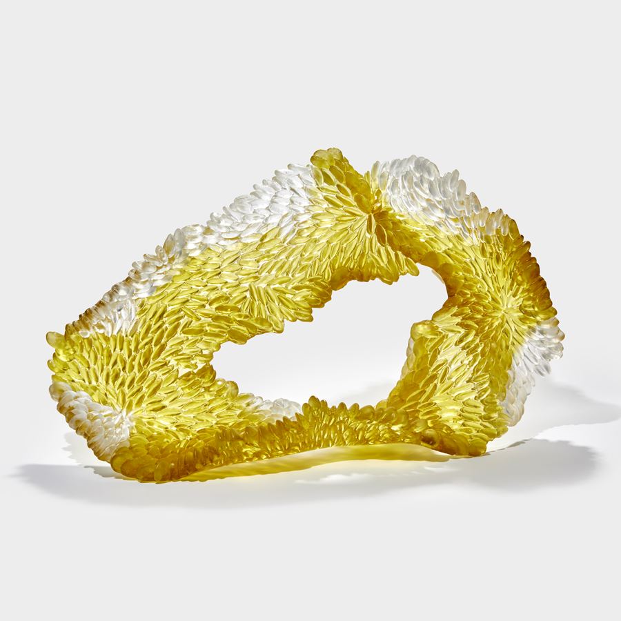 soft squat textured organic rough oval standing form in white and gold yellow with one side shiny the other textured with raised scales hand made from cast glass 