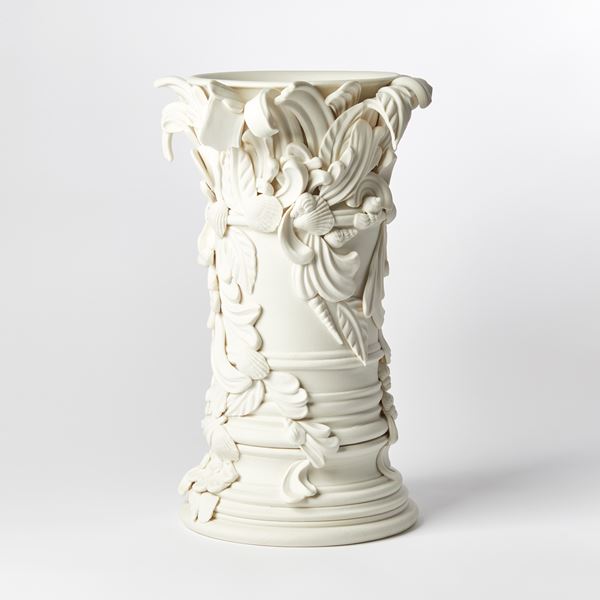 light cream column shaped vase with flared base and top covered in baroque swirls and shells hand made from porcelain