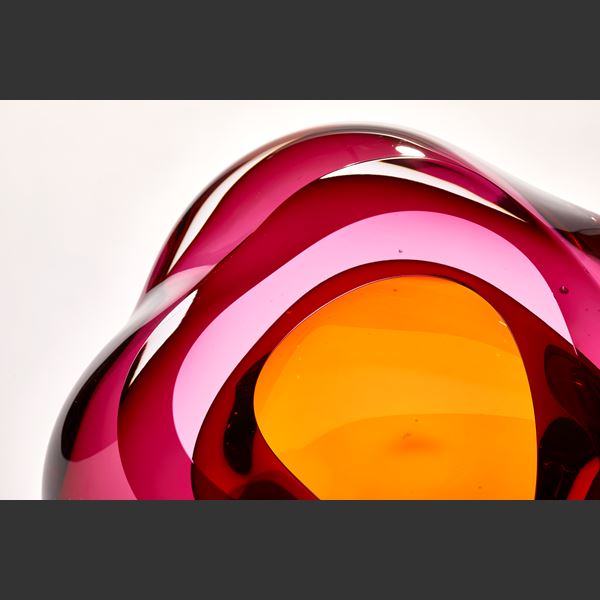 intense transparent pink with an amber gold centre amorphous sculpture with fluid lines and central opening with inner cavity hand made from glass
