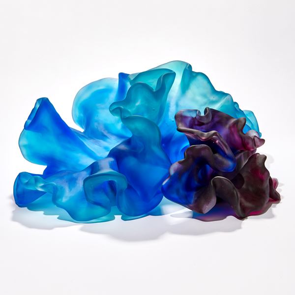 two coral interlocking forms one intense blue the other rich deep purple with the appearance of coral with smooth surfaces and frilled edges hand made from glass