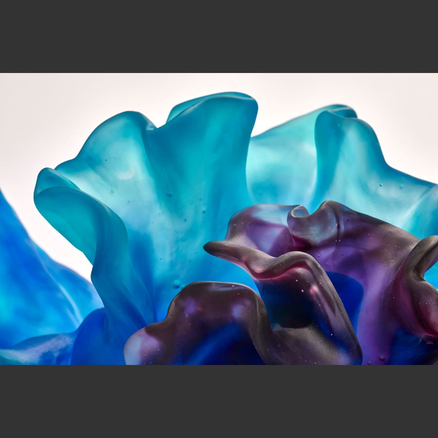 two coral interlocking forms one intense blue the other rich deep purple with the appearance of coral with smooth surfaces and frilled edges hand made from glass