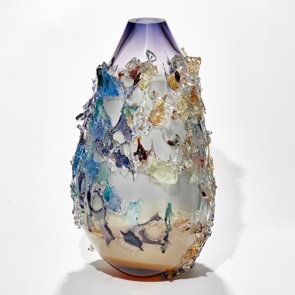 elongated organic teardrop shaped vessel in light apricot white and rich purple with exterior patchy texture in differing colours handmade from glass