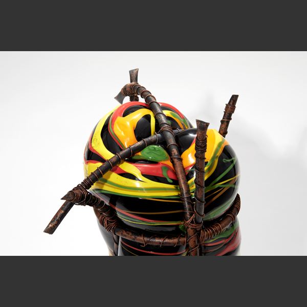 coiled rope base with bulbous abstract figure on top in black yellow red orange and green held within a copper cage handmade from glass
