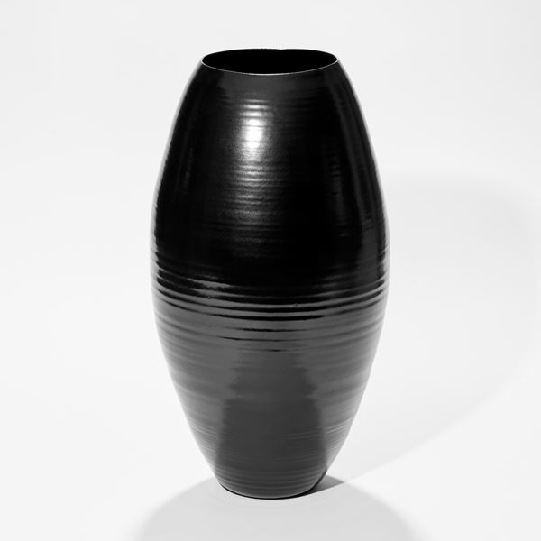 tall rounded oval shiny black vase with inverted front edge with inner curved cut revealing the interior hand made from ceramic