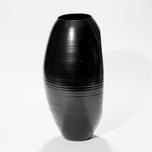 tall rounded oval shiny black vase with inverted front edge with inner curved cut revealing the interior hand made from ceramic