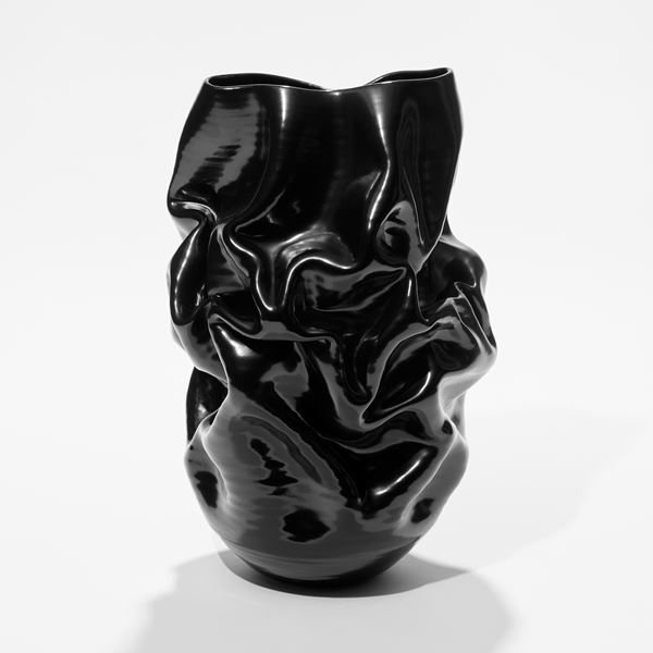 ceramic shiny black crumpled and wrinkled vase with rounded base and uneven top opening lip hand made from white st thomas glazed clay