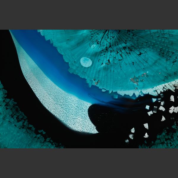 round rich aqua blue and black abstract artwork based on the evil eye amulet hand made from sheet and shattered glass framed in a black steel ring with rectangular base