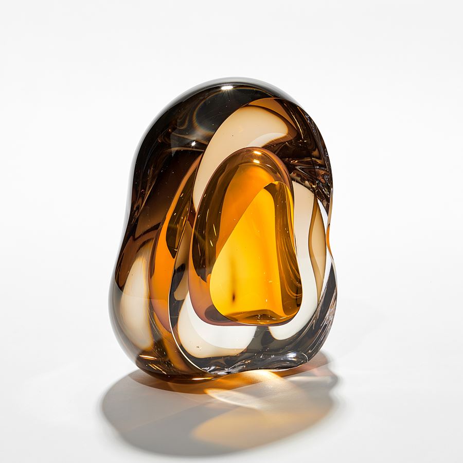 brilliant rich transparent amber amorphous sculpture with central middle organic hole in brilliant gold hand made from glass