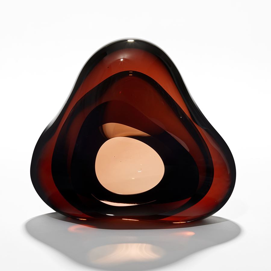 brilliant transparent rich dark amber brown amorphous sculpture with central front facing organic opening hand made from glass