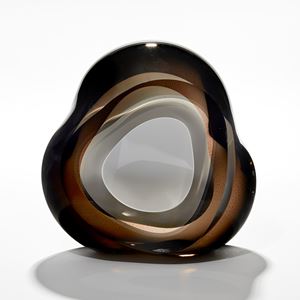 amorphous hand made glass sculpture with central front facing hole layered in opaque white surrounded by layers of rich dark transparent brown and taupe