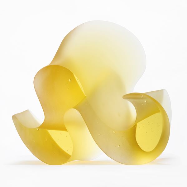 brilliant yellow standing form with two flat shiny sides and sweeping matt curved side with the appearance of a curling thick ribbon or arabic text