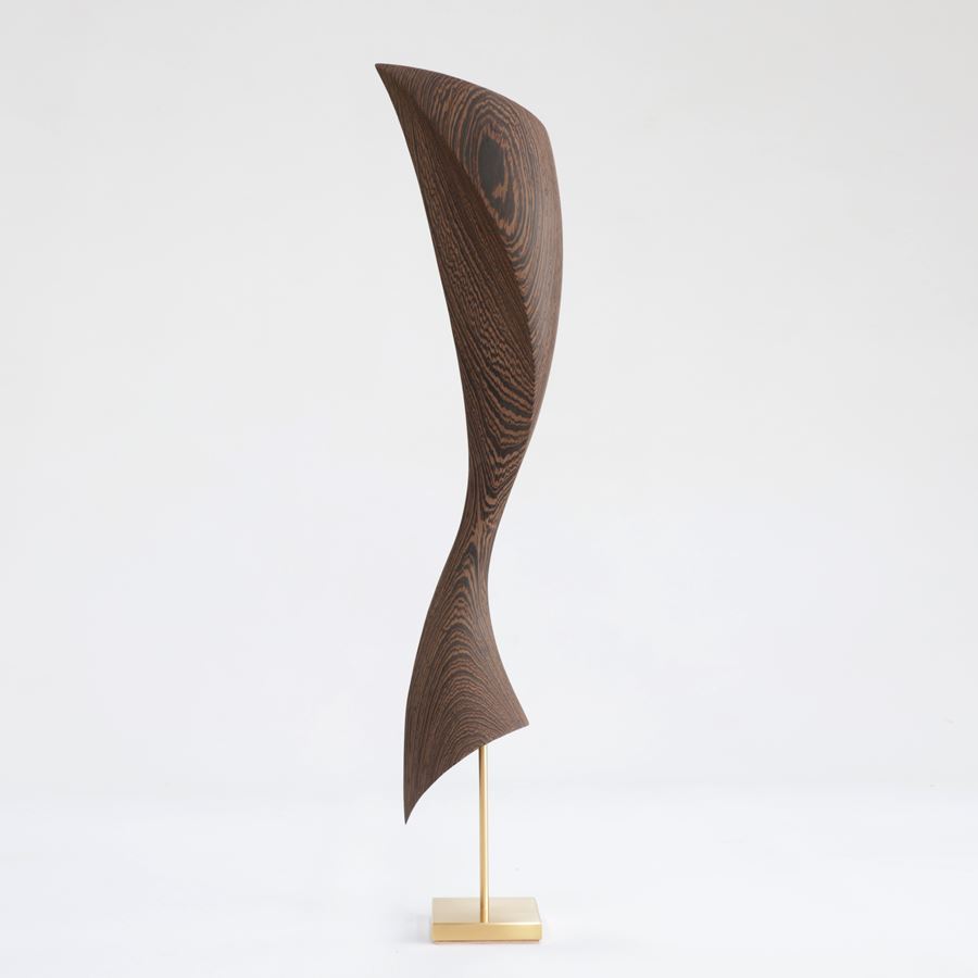 flared dynamic abstract wooden sculpture with gold inlaid in the grain perched on a gold plated stainless steel base