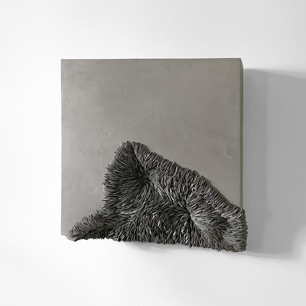 chunky grey square wall mounted large slab sculpture with a surface of smooth plaster with the lower half organically embedded with shards of grey porcelain