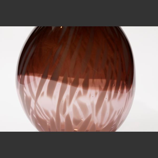 rounded oval transparent vessel with bottom half in soft pink the top in sepia aubergine with an organic abstract feathered surface pattern hand made from glass