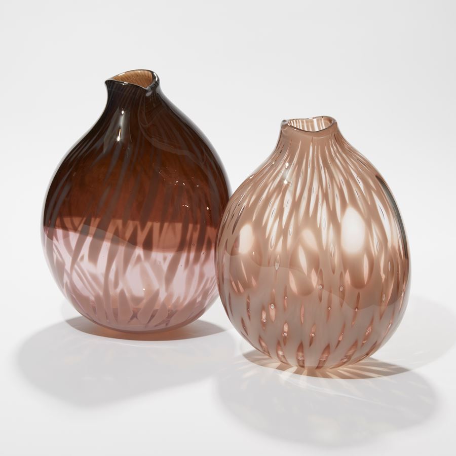 rounded oval transparent vessel with bottom half in soft pink the top in sepia aubergine with an organic abstract feathered surface pattern hand made from glass