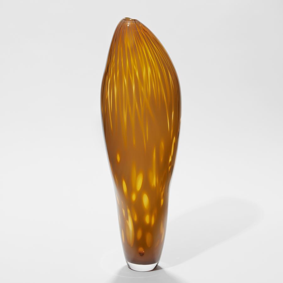 tall asymmetric vessel with gentle pointed top and small opening in rich dark mustard yellow with abstract soft surface patterns hand made from glass