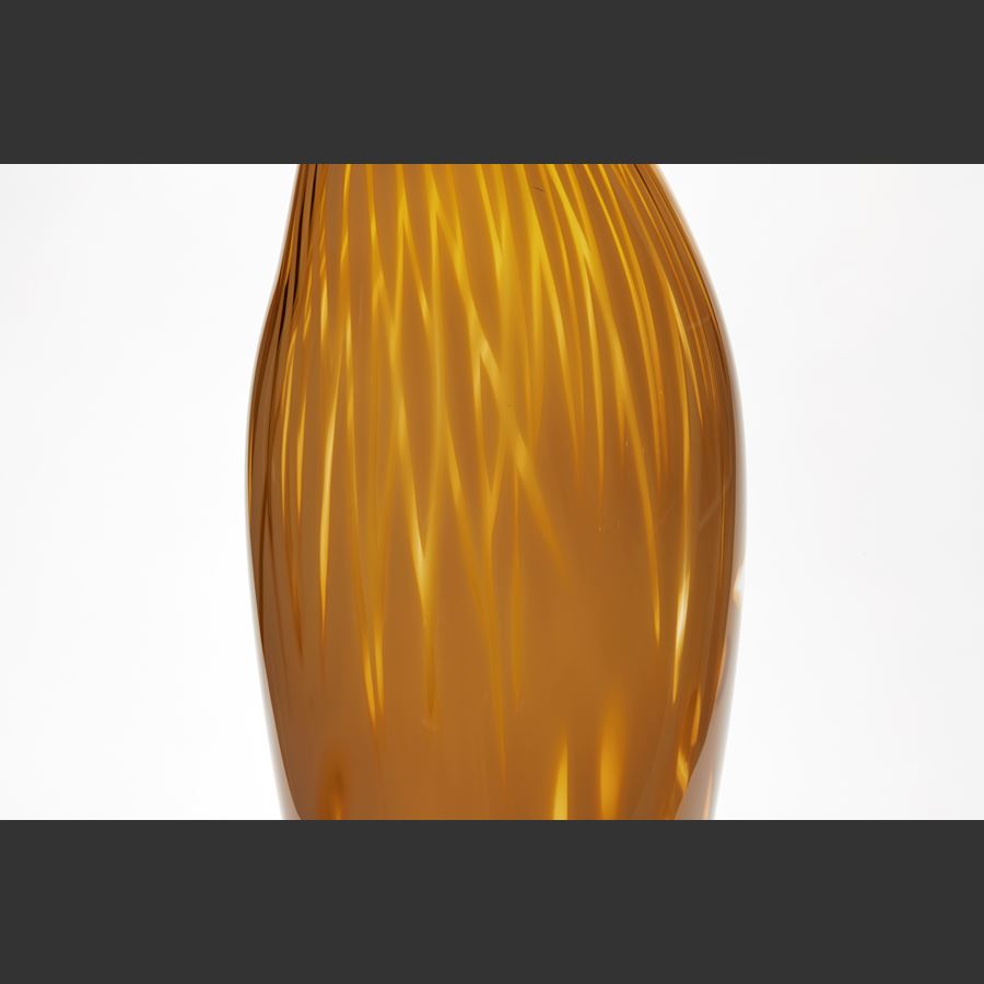 tall asymmetric vessel with gentle pointed top and small opening in rich dark mustard yellow with abstract soft surface patterns hand made from glass