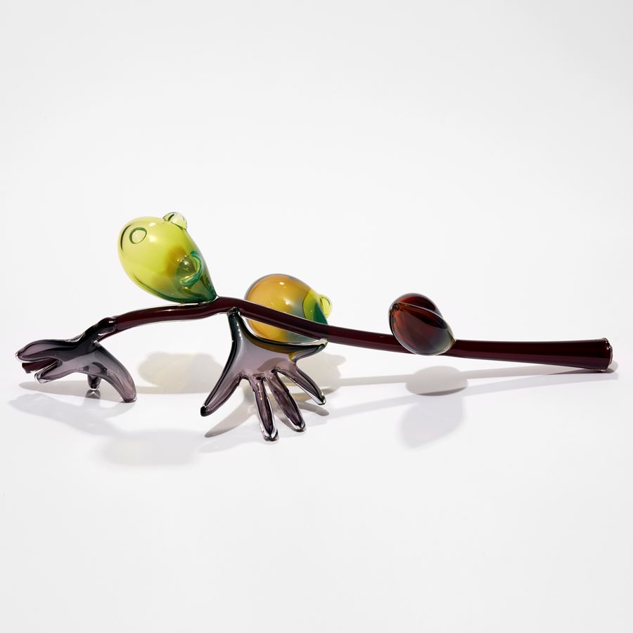 abstract branch with fruits and leaves in brown yellow green and red hand sculpted from glass