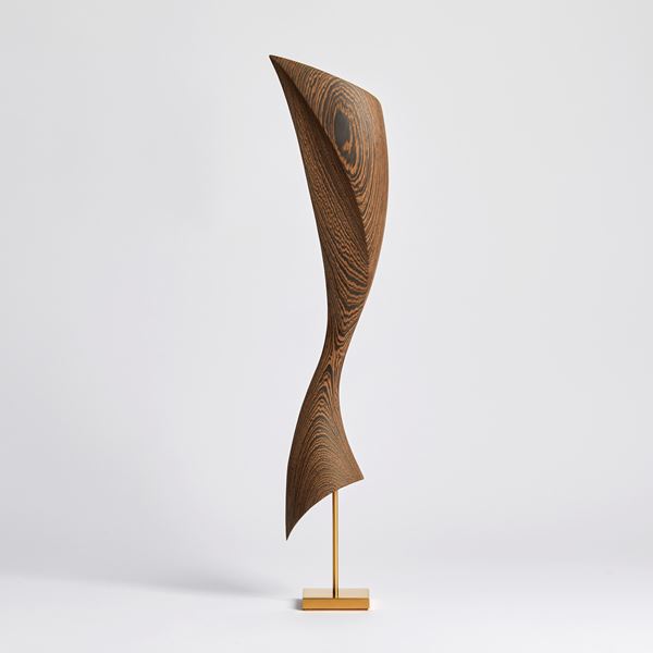 flared dynamic abstract wooden sculpture with gold inlaid in the grain perched on a gold plated stainless steel base
