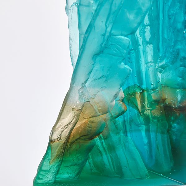 cast glass sculpture resembling a cliff face in jade turquoise blue clear and fawn with two polished outer surfaces and two inner highly textured surfaces