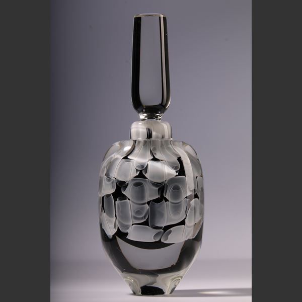 round clear bottle with long stopper with encased abstract pattern in black and white hand made from glass