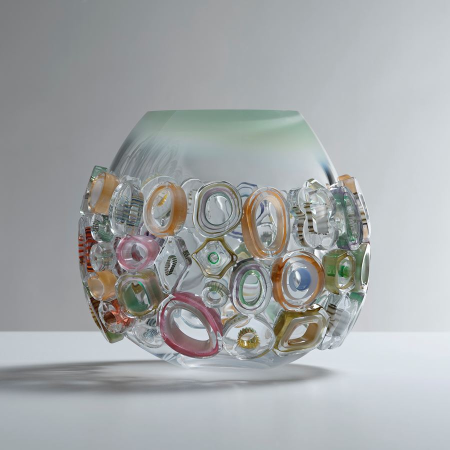 hand blown rounded bowl in clear glass with faded tapering soft jade top edge covered in differently shaped glass murrini rings in various pastel colours 