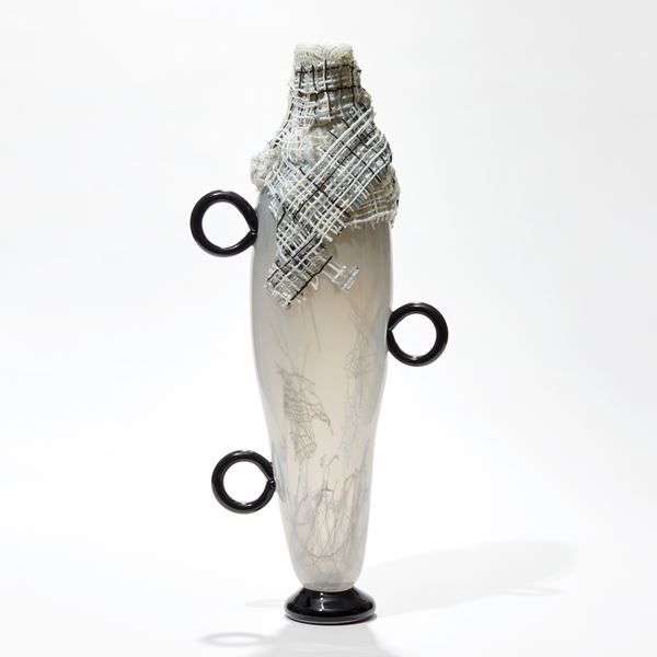 tall abstract figurative jar in opaque soft alabaster with three black rings for handles and neck bound with woven neutral coloured fabric hand made from glass