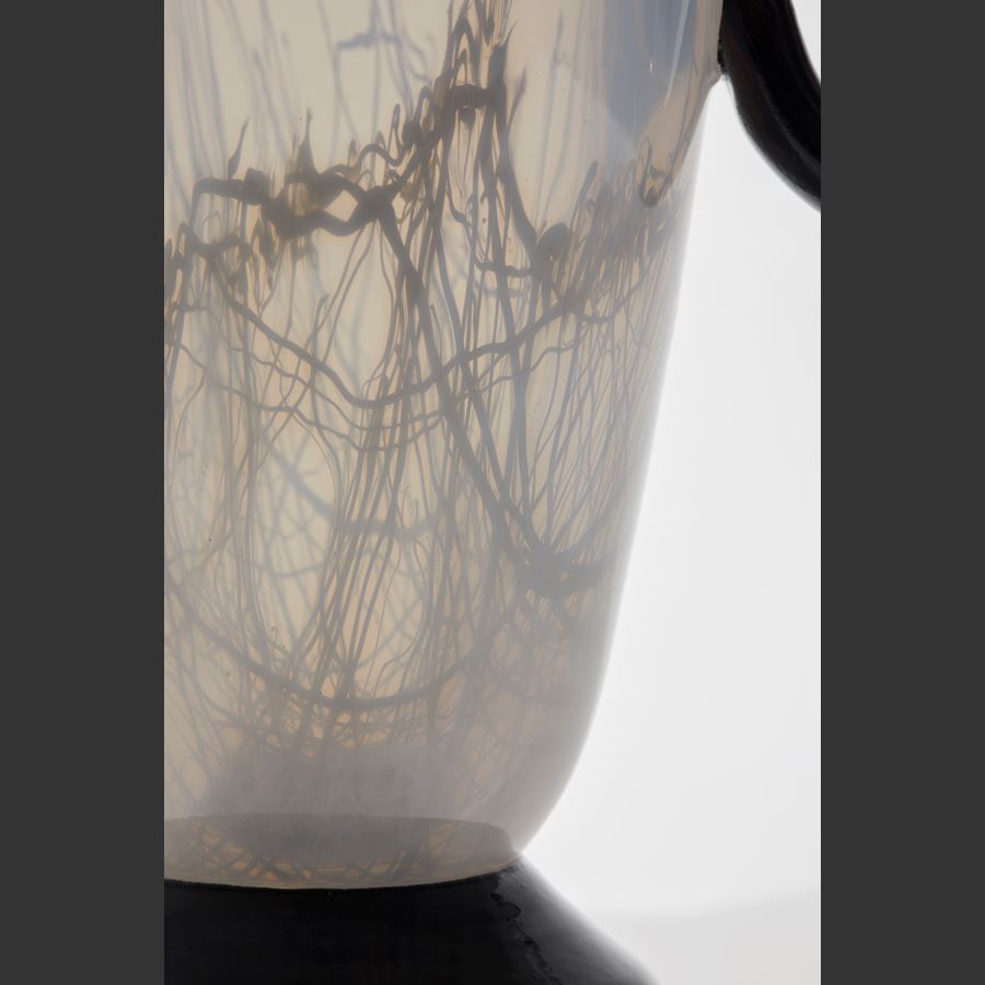 tall abstract figurative jar in opaque soft alabaster with three black rings for handles and neck bound with woven neutral coloured fabric hand made from glass