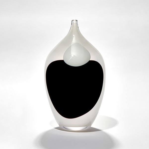 opaque white bottle with long pointed elegant neck with black and white single ink drop marks covering the front hand made from blown glass
