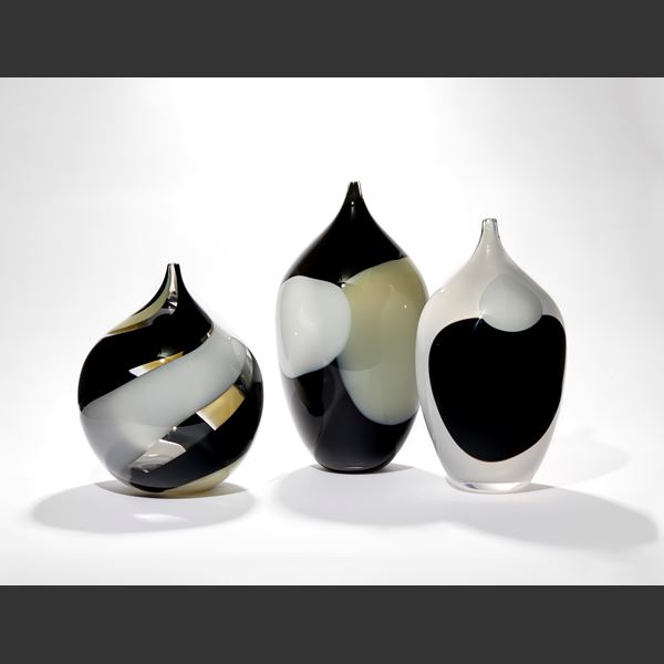 round bottle with pointed neck with fat spiralling stripes in opaque black and opaque white with clear sections hand blown from glass