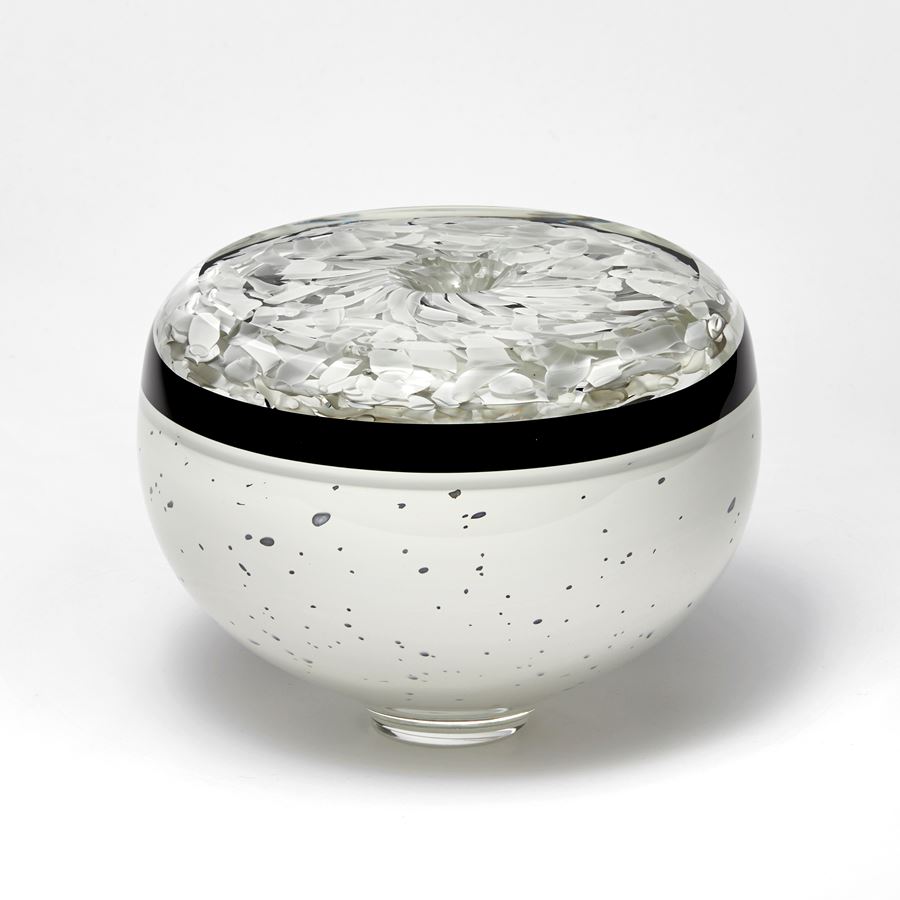 round low vessel with small central hole on the top in black and white with speckled base and mottled top hand made from glass