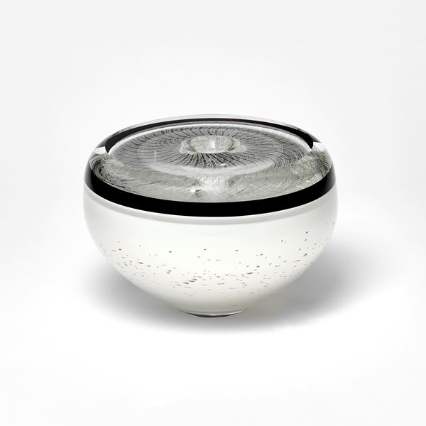 black and white vessel with flat top and rounded sides in black and white with fine filigree pattern on top and speckled base hand made from glass