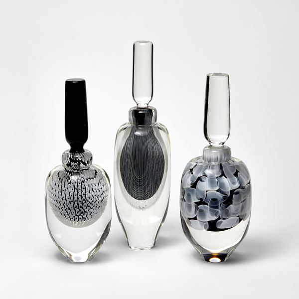 tall clear bottle with stopper with internally trapped fine filigree pattern in white over black hand made from glass